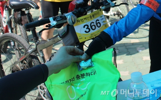 도심 세 곳의 포인트를 경유해 망원유수지에 도착한 참가자들(200명 이내)이 '자전거면 충분하다'라는 도심랠리 완주메달과 기념가방을 받고 있다./사진=박정웅 기자