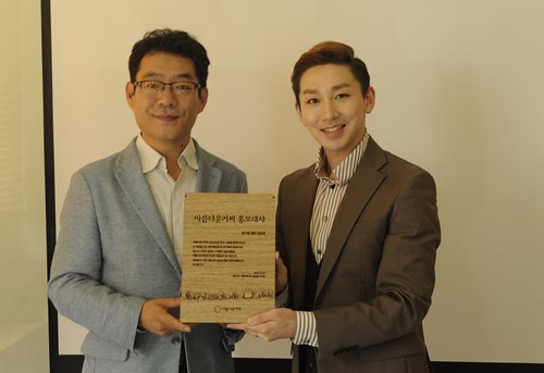▲6일 서울 종로구 돈화문로에 위치한 아름다운커피 본사에서 위촉패를 들고 있는 모습. 아름다운커피의 문정엽 상임이사(사진 좌)와 뮤지컬 배우 김호영 씨(사진 우) 