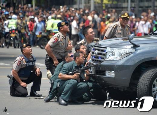 '자카르타 테러' 인도네시아 수도 자카르타의 도심 쇼핑몰 인근에서 14일 수차례 폭발이 발생해 최소 3명이 숨진 가운데 현지 경찰이 차량 뒤에 숨어서 상황을 지켜보고 있다. /사진=뉴스1(AFP 제공)