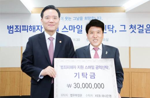 함영주 KEB하나은행장(오른쪽)이 김현웅 법무부 장관(왼쪽)으로부터 '범죄피해자 지원 스마일 공익신탁' 제1호 신탁을 받고 있는 모습./사진=KEB하나은행