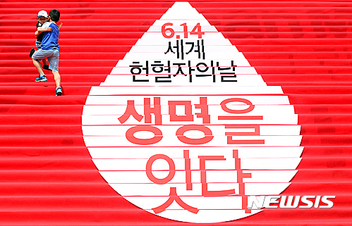 오늘(14일) 세계 헌혈의 날을 기념해 '생명을 잇다'라는 문구가 쓰여진 서울 종로구 세종문화회관 계단을 어린이들이 오르고 있다. /사진=뉴시스