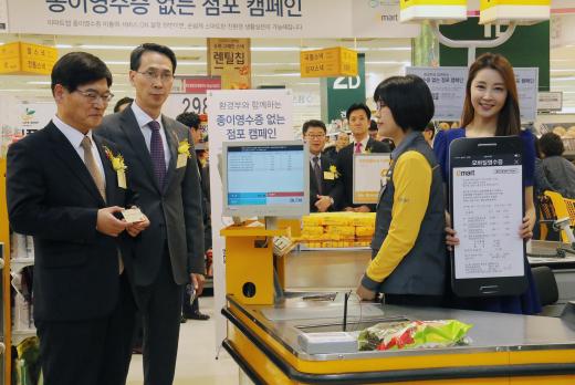19일 오전 서울 성동구 이마트 성수점에서 '종이영수증 없는 점포 캠페인'이 펼쳐진 가운데 조경규 환경부 장관(좌측)과 이갑수 이마트 대표이사(좌측에서 두번째)가 모바일영수증을 시연해 보고 있다.