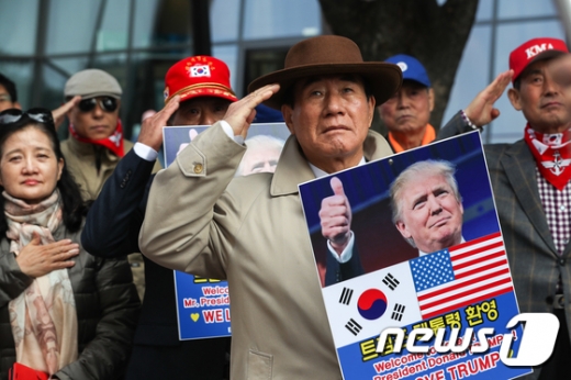지난 3일 오전 서울 종로구 광화문역 앞에서 열린 '트럼프 환영 집회'에서 전국구국동지회 회원들이 트럼프 대통령 방한을 환영하는 손피켓 및 태극기와 성조기를 들고 국기에 대한 경례를 하고 있다. /사진=뉴스1