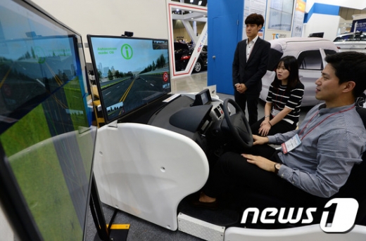 지난 5월 경기도 고양시 킨텍스에서 열린 '2017 국토교통 기술대전'에서 교통안전공단 부스 관계자들이 자율주행차 도로주행 시뮬레이터를 소개하고 있다./사진=뉴스1DB
