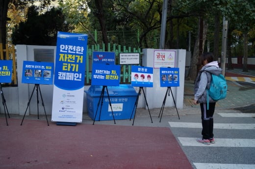 윤중초등학교에 마련된 캠페인 홍보물을 한 학생이 관심을 갖고 지켜보고 있다. /사진=대한자전거연맹