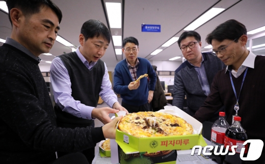 ▲ 기획재정부 직원들이 6일 정부세종청사 기재부 내 사무실에서 문재인 대통령이 보낸 피자를 먹고 있다. 문 대통령은 이 날 내년도 예산안과 세제개편안 등으로 격무에 시달린 직원들에게 고마움의 표시로 피자 350판을 기재부에 보냈다. 2017.12.6/뉴스1(세종=뉴스1) 장수영 기자 / presy@