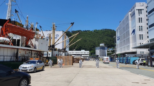 지난 23일 오후 부산 감천항에 정박한 러시아 국적 냉동화물선에서 코로나19 양성 판정을 받은 선원들이 부산의료원 이송을 위해 부산재난본부 차량에 탑승을 마치자 방역 관계자들이 방역작업을 진행하고 있다. /사진=뉴스1