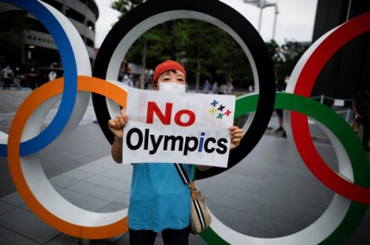 24일 일본 도쿄 시가지에 설치된 도쿄올림픽 조형물 앞에 한 시민이 올림픽 개최 반대 문구가 쓰인 피켓을 든 채 시위를 벌이고 있다. /사진=로이터
