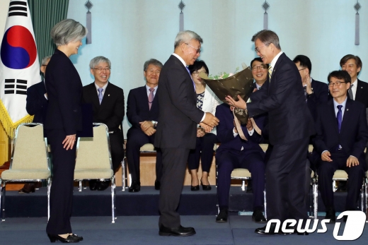 문재인 대통령이 18일 오후 청와대에서 열린 강경화 외교부장관 임명식에서 강 장관의 남편인 이일병 교수에게 꽃다발을 주고 있다.(청와대) 2017.6.18/뉴스1 © News1 이광호 기자