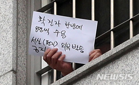 지난 29일 서울 송파구 동부구치소에서 한 수용자가 창 밖의 취재진을 향해 메시지가 적힌 종이를 흔들어보이고 있다. /사진=뉴시스