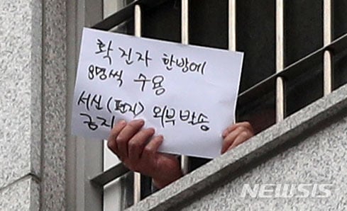 지난 29일 서울 송파구 동부구치소에서 한 수용자가 창 밖의 취재진을 향해 메시지가 적힌 종이를 흔들어보이고 있다. /사진=뉴시스