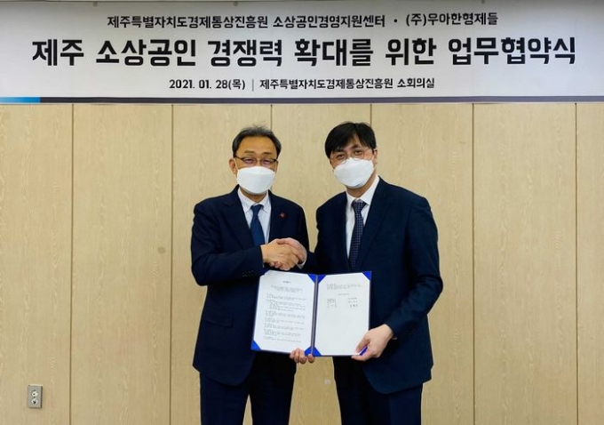 우아한형제들 함윤식 고객중심경영부문장(오른쪽)과 제주경제통상진흥원 문관영 원장이 28일 제주시에 위치한 제주경제통상진흥원에서 ‘제주 소상공인 경쟁력 확대를 위한 업무 협약(MOU)’을 체결하고 기념촬영 하고 있다. (우아한형제들 제공)