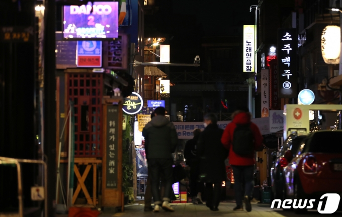 수도권의 사회적 거리두기가 2단계로 완화된 15일 저녁 서울 용산구 이태원 거리에 불 켜진 간판 사이로 시민들이 지나가고 있다.  2021.2.15/뉴스1 © News1 이동해 기자