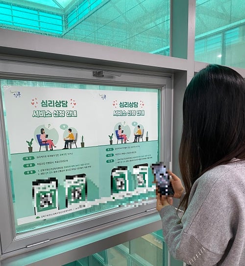 한 주민이 복지시설에 붙은 포스터의 QR코드를 찍고 있다./사진제공=강북구