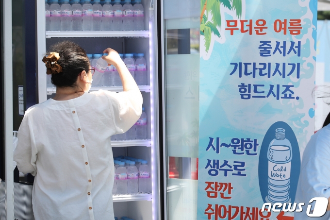 지난달 21일 서울 노원구 코로나19노원구민의전당 임시선별검사소에서 한 시민이 폭염대비 야외 힐링 냉장고에서 시원한 생수를 꺼내고 있다. 노원구는 무더위쉼터 및 코로나19 선별검사소에 힐링냉장고 두고 주민들에게 시원한 생수를 공급한다. 2021.7.21/뉴스1 © News1 임세영 기자