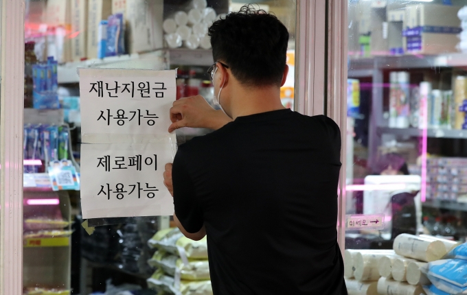 ‘코로나 상생 국민지원금’ 지급 절차가 6일부터 시작된다. 사진은 서울 마포구 공덕역 인근에 있는 한 식당 주인이 재난지원금 사용 가능 안내문을 붙이는 모습. /사진=뉴시스