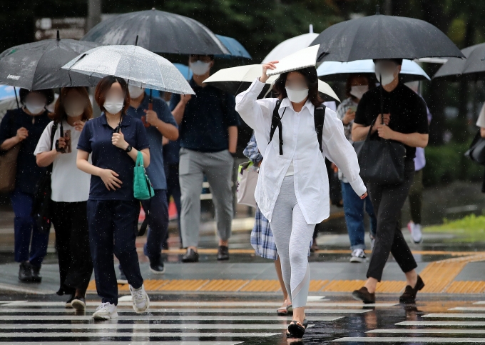 7일은 전국이 흐리고 천둥과 번개를 동반한 비가 내린다. 사진은 지난달 8월 광화문거리에서 한 시민이 스케치북으로 비를 피하며 출근하는 모습. /사진=뉴스1