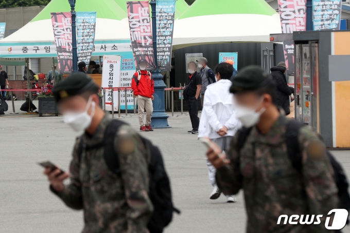 27일 서울 중구 서울역광장에 마련된 신종 코로나바이러스 감염증(코로나19) 임시선별진료소 앞에서 군인들이 발걸음을 옮기고 있다. 이날 국방부는 30세 이상 군 장병 등에 대한 신종 코로나바이러스 감염증(코로나19) 백신 접종을 오는 28일 시작해 5월 첫째 주까지 마무리할 계획이라고 밝혔다. 2021.4.27/뉴스1 © News1 황기선 기자