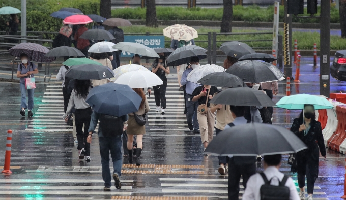 월요일인 내일(8일)은 전국에 천둥·번개를 동반한 비가 내리고 강풍이 불어 매우 쌀쌀할 전망이다. 사진은 시민들이 우산을 쓰고 횡단보도를 건너고 있는 모습./사진제공=뉴시스