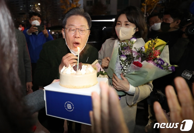 이재명 더불어민주당 대선후보와 배우자 김혜경 씨가 27일 전남 순천시 연향동 패션의 거리에서 시민들로부터 받은 생일 케이크의 촛불을 끄고 있다. 이 후보의 생일은 음력 1963년 10월23일이다. 2021.11.27/뉴스1 © News1 이동해 기자