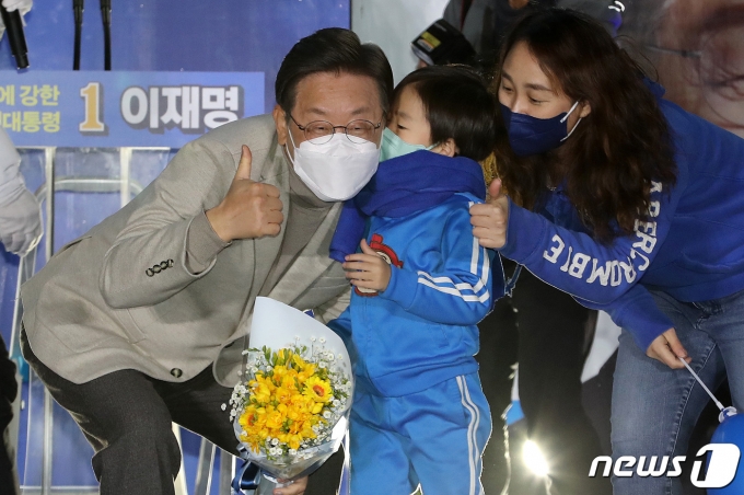 이재명 더불어민주당 대선 후보가 28일 저녁 경북 안동시 웅부공원에서 열린 '안동의 아들 이재명, 대통령으로 키웁시다' 안동 유세에서 한 아이에게 꽃다발을 받은 뒤 기념사진을 찍고 있다. 2022.2.28/뉴스1 © News1 이동해 기자