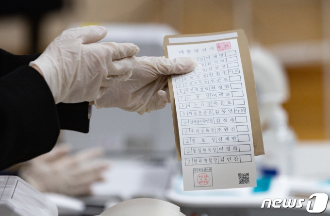 제20대 대통령선거 사전투표일인 4일 오전 서울 서초구 반포1동 주민센터에 마련된 사전투표소를에서 선거관리위원회 직원이 유권자에게 투표용지를 전달하고 있다. 2022.3.4/뉴스1 © News1 이재명 기자