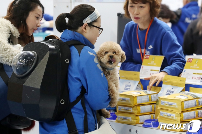 29일 서울 강남구 세텍(SETEC)에서 열린 '2019 케이펫페어'에서 반려동물을 동반한 관람객들이 사료를 고르고 있다. 2019.3.29/뉴스1 © News1 민경석 기자