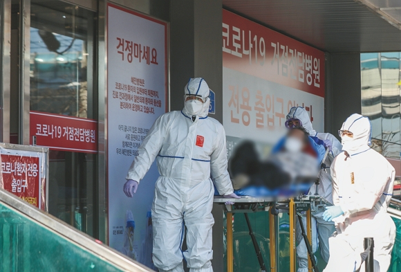정부가 코로나19 감염병 전담병원의 병상을 단계적으로 감축한다. 코로나19 확진 환자를 이송하는 소방 구급대원들 모습./사진=뉴스1