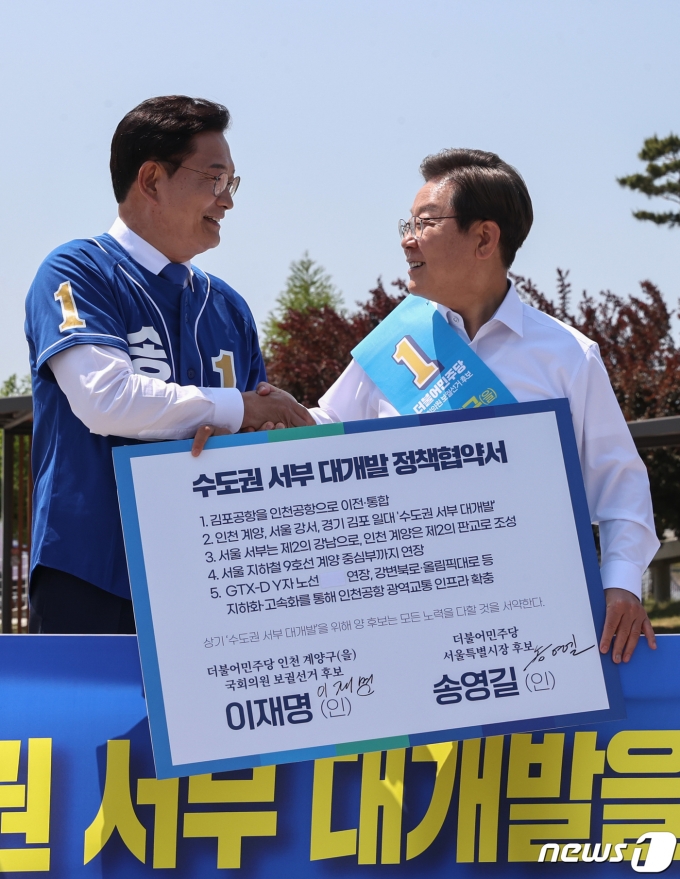 송영길 더불어민주당 서울시장 후보, 이재명 인천 계양을 국회의원 후보가 지난 5월 27일 김포시 고촌읍 아라 김포여객터미널 아라마린센터 앞 수변광장에서 열린 김포공항 이전 수도권 서부 대개발 정책협약 기자회견에서 정책협약서에 서명한 뒤 악수를 나누고 있다. © News1 국회사진취재단