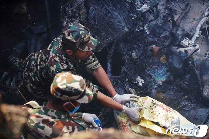 15일 네팔에서 추락한 항공기에서 군인들이 사람들을 구조하고 있다. ⓒ AFP=뉴스1
