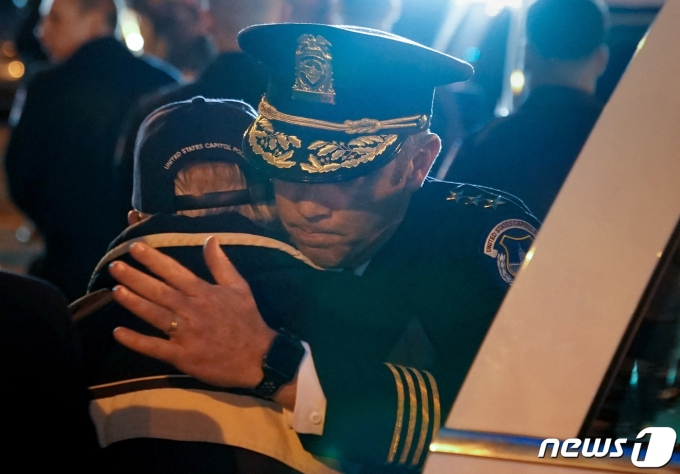 1·6 미국 의회의사당 폭동 사태로 숨진 고(故) 브라이언 시크닉 경찰관의 아버지 찰스 시크닉(뒷모습)이 당시 아들에게 후추스프레이 공격을 가한 줄리안 카테르의 유죄판결을 보고 나와 아들 동료의 포옹을 받고 있다. 2023.01.27 ⓒ 로이터=뉴스1 ⓒ News1 정윤미 기자
