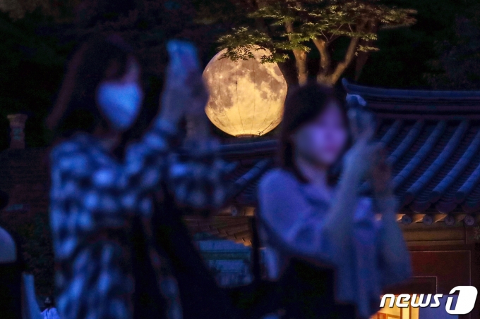 지난해 9월9일 서울 종로구 창경궁에서 열린 ‘궁궐에 내려온 보름달’ 행사를 찾은 관람객들이 양화당 풍기대에 설치된 보름달 모양 조명을 배경으로 기념촬영을 하고 있다. 2022.9.9/뉴스1 ⓒ News1 민경석 기자