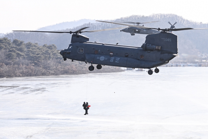 HH-32 탐색구조헬기(오른쪽)가 구조용 인양기(HOIST)로 조난자를 구조하고 있다.(공군 제공)