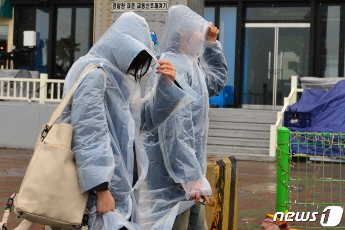 12일 오후 경북 포항시 북구 영일대해수욕장을 찾은 관광객들이 갑자기 내린 비에 일회용 비옷을 입고 걸어가고 있다.2023.3.12/뉴스1 ⓒ News1 최창호 기자