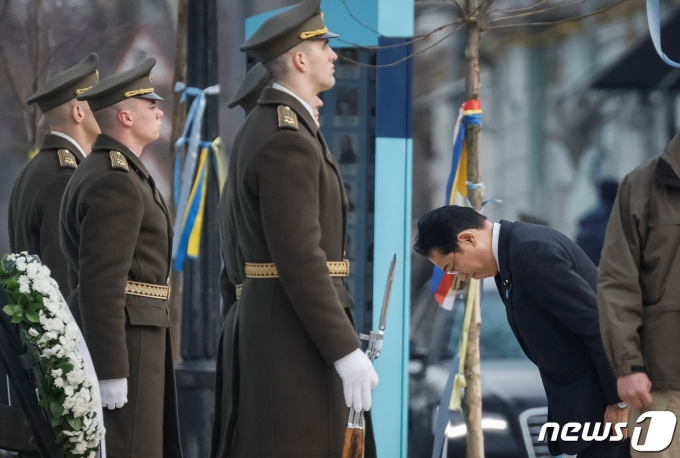 21일(현지시간) 우크라이나 수도 키이우 외곽 소도시 부차에 마련된 우크라이나군 추모의 벽 앞에서 묵념을 하고 있다. 2023.3.21 ⓒ 로이터=뉴스1 ⓒ News1 정윤미 기자