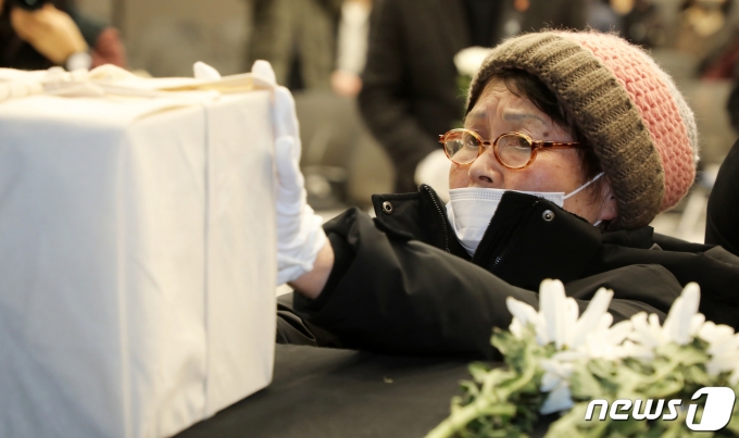 제주4·3 희생자 신원 확인 보고회에서 한 유족이 유해함을 붙잡고 있다. ⓒ News1