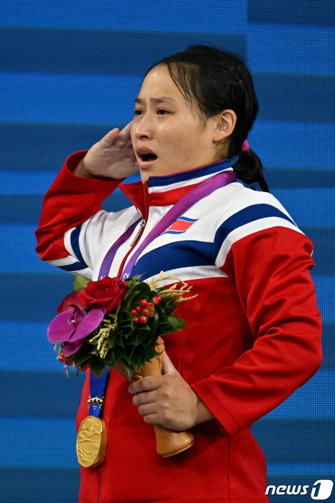 북한 리성금이 9월30일 열린 2022 항저우 아시안게임 역도 여자 49㎏급에서 우승한 뒤 시상대에서 거수경례를 하고 있다. ⓒ AFP=뉴스1