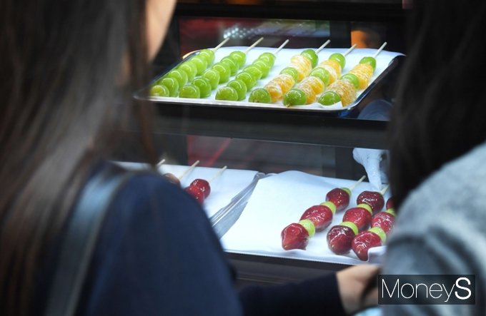 한국소비자원 등이 탕후루를 포함, 시중에서 판매하는 카페 음료 등의 당류 함량을 직접 조사했다. 지난 18일 서울 마포구 홍익대학교 일대에서 젊은 소비자들이 탕후루를 구매하는 모습. /사진=장동규 기자
