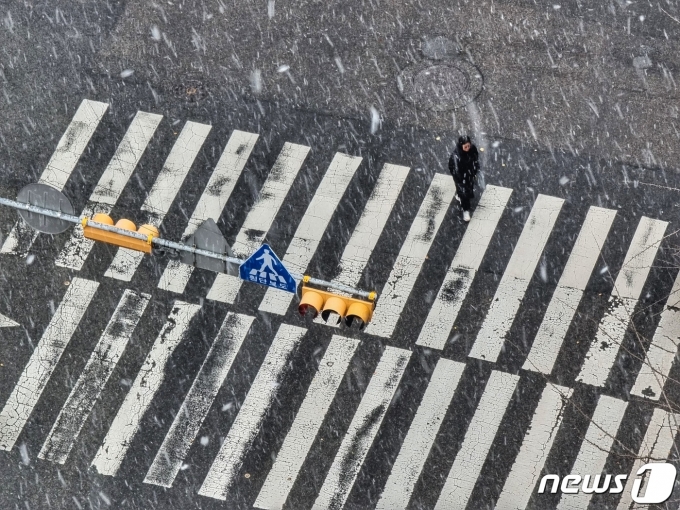 지난달 경기 고양 덕양구에 눈이 내리는 가운데 한 시민이 횡단보도를 건너고 있다.  ⓒ News1 황덕현 기후환경전문기자