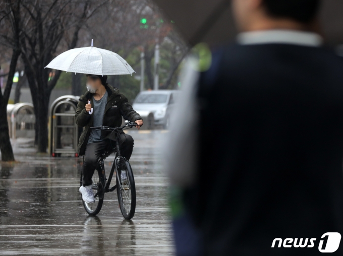 겨울비가 내리는 11일 부산 해운대구 벡스코 인근에서 한 시민이 우산을 든 채 자전거를 타고 있다. 2023.12.11/뉴스1 ⓒ News1 윤일지 기자