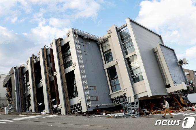 4일(현지시간) 일본 이시카와현 와지마시에서 한 남성이 지진으로 쓰러진 건물 앞을 지나가고 있다. 혼슈 중서부 이시카와현 노토반도에서는 지난 1일 오후 4시 10분쯤 규모 7.6 강진이 발생했다. 2024.01.04 ⓒ 로이터=뉴스1 ⓒ News1 최종일 기자