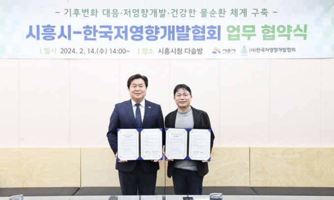 임병택 시흥시장과 최경영 한국저영향개발협회장이 협약서를 들고 기념사진을 찍고 있다. / 사진제공=시흥시