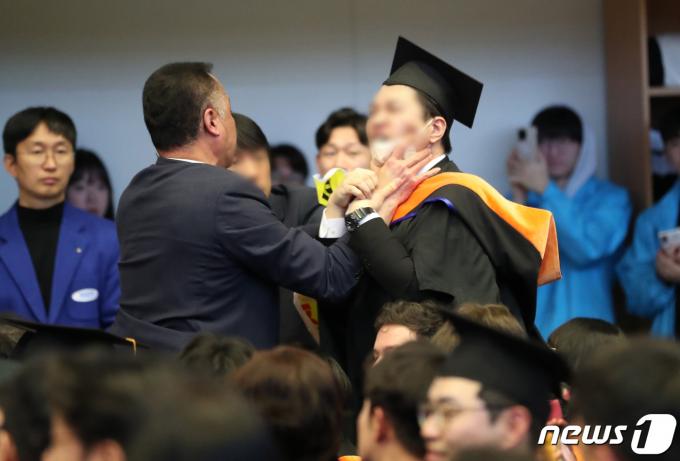 16일 오후 대전 유성구 한국과학기술원(KAIST)에서 열린 2024년 학위수여식에서 한 졸업생이 윤석열 대통령에게 항의하자 경호원들로부터 제지를 당하고 있다. (대전충남공동취재단) 2024.2.16/뉴스1 ⓒ News1 김기태 기자