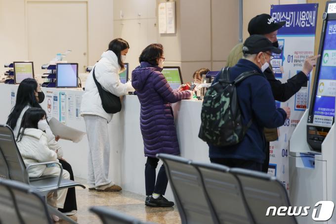 정부의 의대 정원 확대에 반발하는 전공의(인턴·레지던트)들의 집단 진료거부로 인해 의료대란이 우려되고 있는 21일 서울의 한 병원에서 환자와 보호자들이 수납 창구에서 대기하고 있다. 2024.2.21/뉴스1 ⓒ News1 민경석 기자