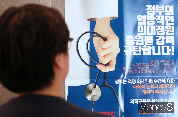 ▲정부 의대 증원 규탄 글귀 바라보는 의료 관계자.
