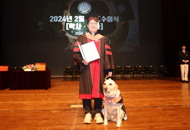 23일 경북대 대강당에서 열린 2024년 2월 학위수여식에서 시각장애인 김경훈 씨가 명예졸업장을 받은 안내견 '탱고'와 함께 기념촬영을 하고 있다. /사진제공=경북대학교