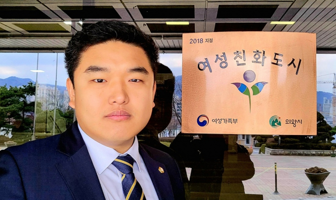 의왕시의회 한채훈 의원이 지난 2018년도에 지정된 '여성친화도시 인증패' 앞에서 사진촬영 했다. / 사진제공=의왕시의회