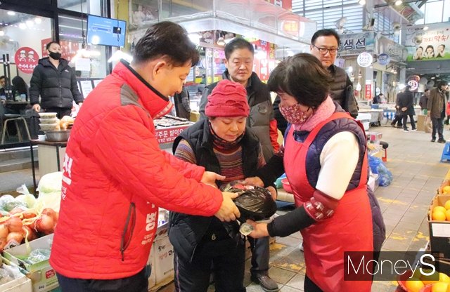 권영진 국민의힘 대구 달서 병 국회의원 예비후보(왼쪽)가 월촌역시장 장보기행사에서 과일을 구매하고 있다./사진=김덕엽 기자