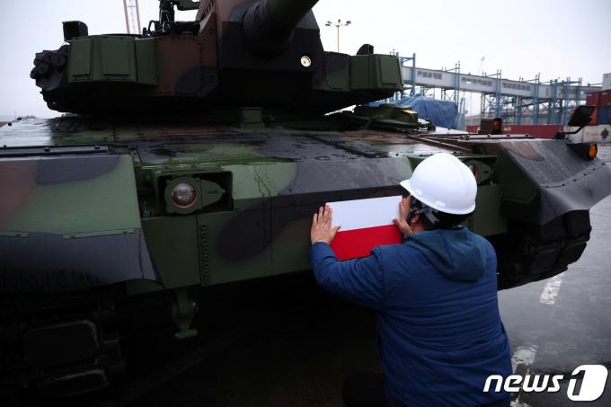 2022년 12월 폴란드 그디니아 항구에 한국산 K2 전차와 K9자주포가 처음 입고됐다. 현장 노동자가 폴란드 국기가 그려진 스티커를 전차에 부착하고 있다. 2022.12.7. ⓒ 로이터=뉴스1 ⓒ News1 권진영 기자
