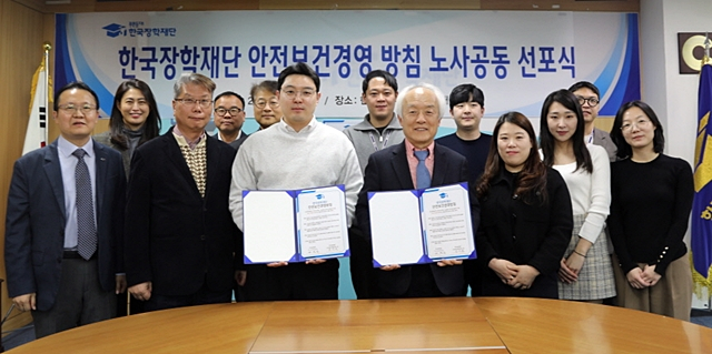 배병일 한국장학재단 이사장(앞줄 오른쪽 네번째)과 황수환 노조 위원장(앞줄 오른쪽 다섯번째)이 20일 장학재단 대구 본사 회의실에서 열린 안전보건경영방침 선포식에서 각각 서명한 안전보건경영방침을 들어보이고 있다./사진제공=한국장학재단